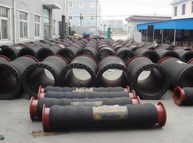 Several rows of dredge hoses are on the ground.